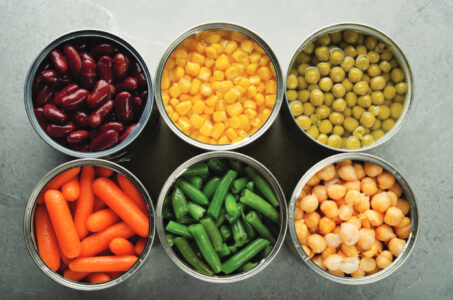 Flat lay view at canned carrots, chickpeas, kidney beans, green beans, peas and corn in…